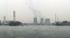 View across river, featuring several large smokestacks.