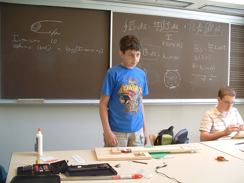 Student standing in front of guitar physics equations.