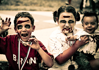 Three kids dressed in zombie costumes posing for the camera.