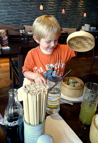 A photograph of a child eating dim sum.