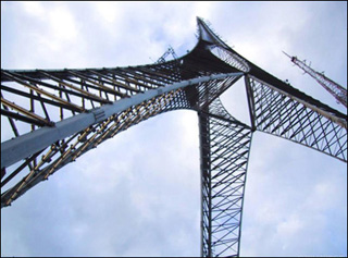 A tall, three-footed tower stretching into blue sky.