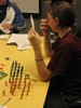 Blue and pink toy soldiers are lined up on the desk while a student looks at his hand of index cards.