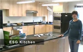 A woman in a blue sweater places her hand on the counter of a kitchen.