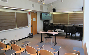 View from the back of the classroom toward the screen and two pianos in front.