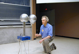 Professor Walter Lewin photographed during a demonstration, bouncing a balloon between his head and a small Van de Graaff generator.