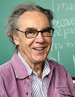 A headshot of Prof. Walter Lewin wearing a striped shirt with a pink jacket over it.