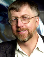 A headshot of Prof. Martin Connors wearing a suit jacket with a button down shirt, open at the collar.