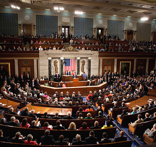 The members of Congress and the Senate are seated together in a half circle, listening to the President give an address.