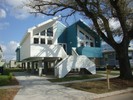 A modern blue and white home that is elevated above the ground to prevent future flooding.