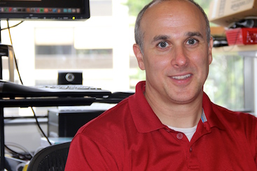 A man in a red shirt in front of a window.