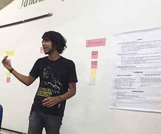 A photo of a man standing at the front of a classroom, discussing community research.