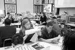 Photograph of Ms. Freeman dividing her class into groups of four and handing each group a packet of reading material.