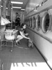 Photograph of a variety of people and personalities doing laundry at the laundromat.