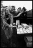 Photo of an vendor smiling as he leans on a stick next to his table of antique photographs.