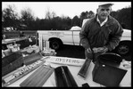 Photograph of a man in a baseball cap laying out charming, hand-made signs on a table.