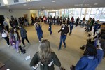 Several high school aged girls are standing in a large circle. A few girls are walking in the middle of the circle.