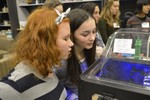 Girls are looking at a 3D printer.