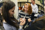 A girl is holding a 3D printed miniature Eiffel Tower. Another girl is discussing the object with her.