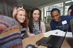 Several girls are sitting around a computer with a volunteer.