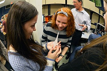 Three young women examine a 3D printed model of the Eiffel Tower.